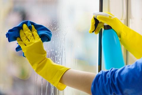 person cleaning window with spray