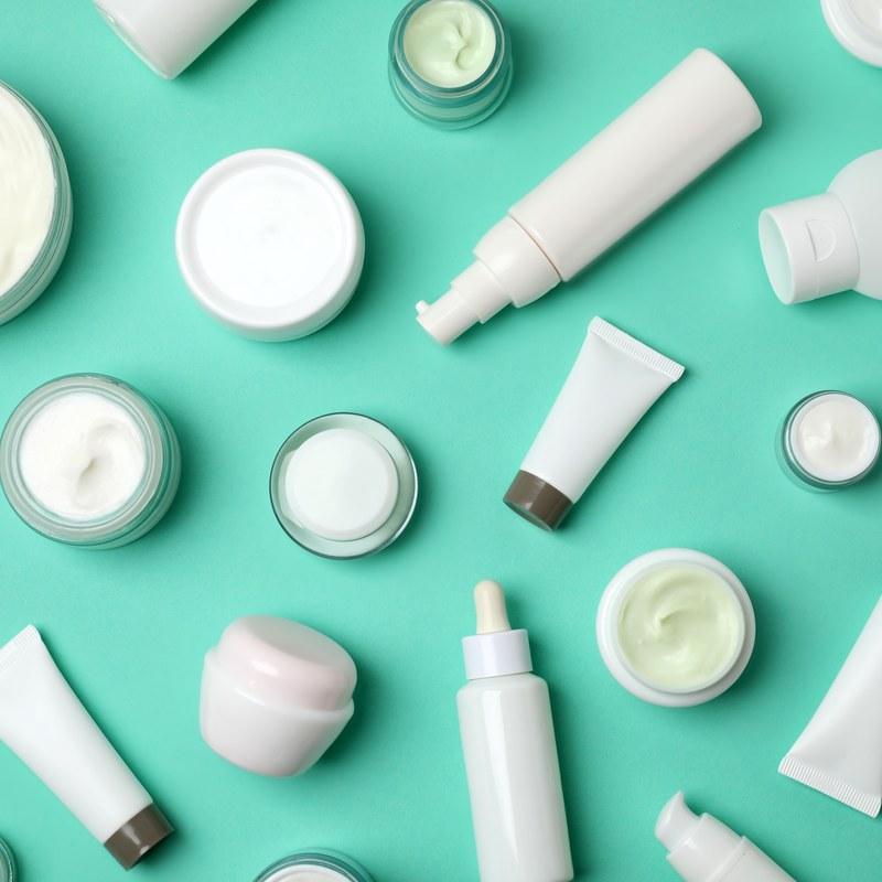 Personal care cream jars and tubes on a teal background