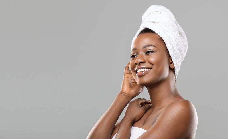 Woman in a towel smiling and touching her face