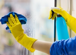 person cleaning window with spray